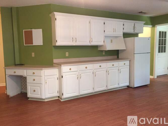A kitchen with white cabinets and a green wall.