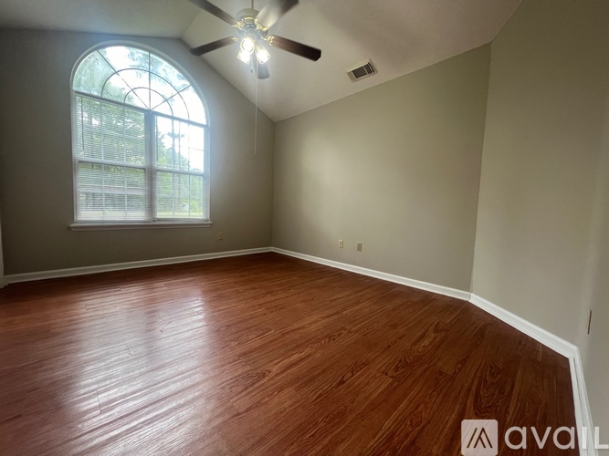 A room with wooden flooring and a ceiling fan.