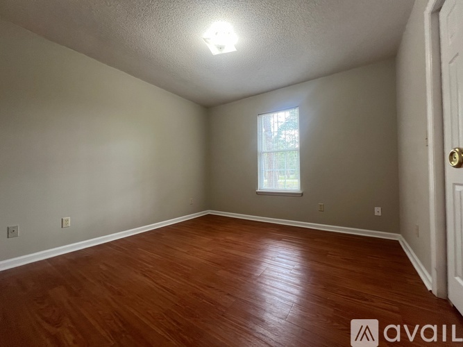 A room with wooden flooring and a window letting in natural light.