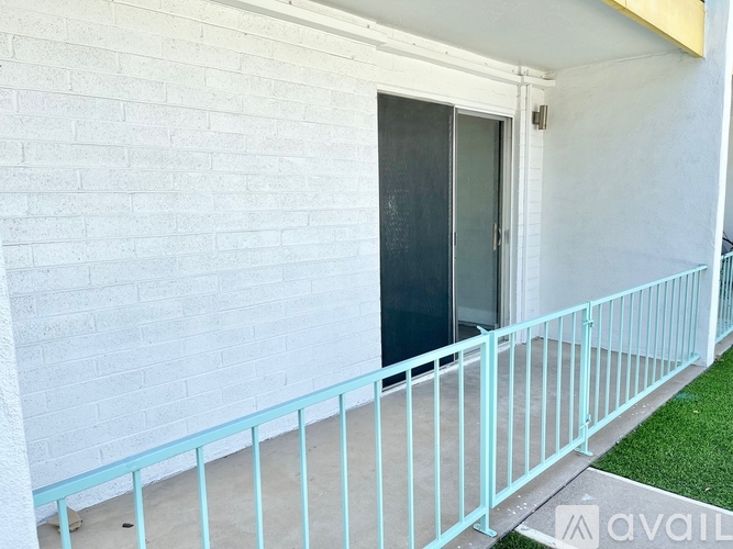 A white building with a black door and a blue railing.