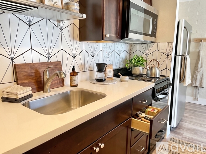A kitchen with a white sink and brown cabinets.