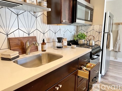 A kitchen with a white sink and brown cabinets.