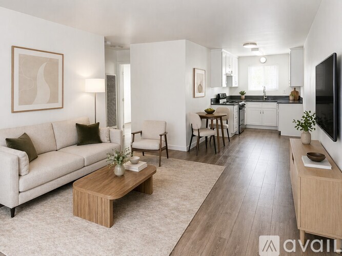 A living room with a white couch, a wooden coffee table, and a kitchen area in the background.