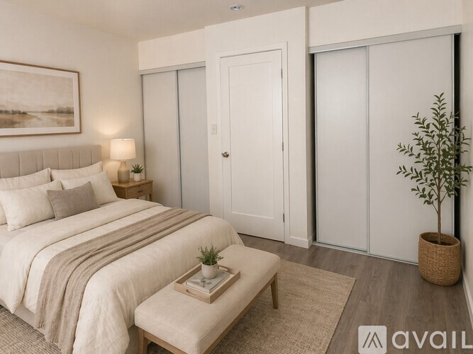 A bedroom with a large bed, a nightstand with a lamp, a small table with a plant, and a woven basket on the floor.