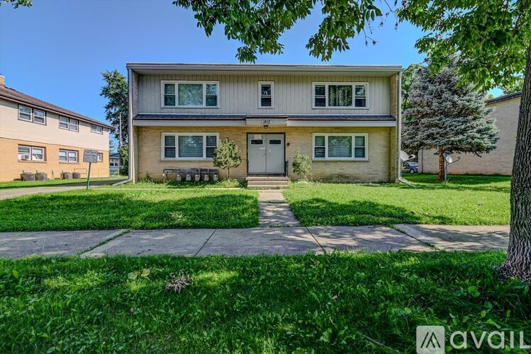 A two-story house with a front yard and a tree.