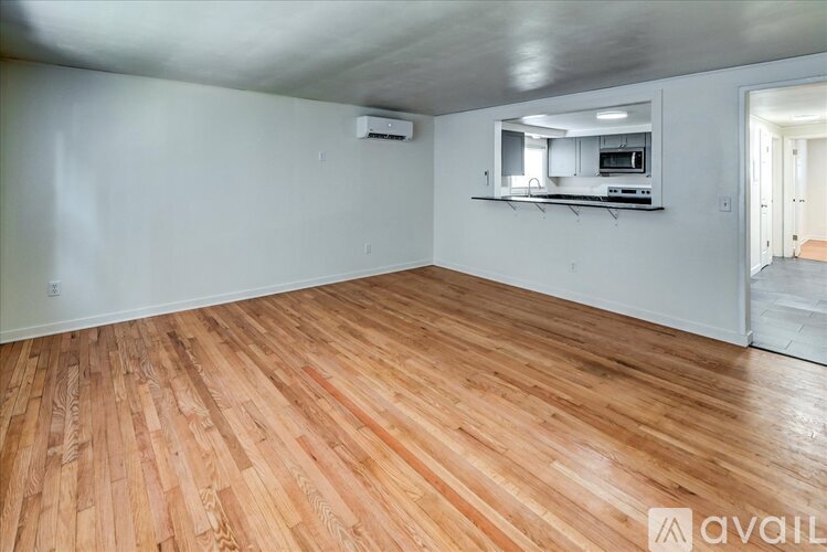 A room with wooden flooring and a kitchenette in the corner.