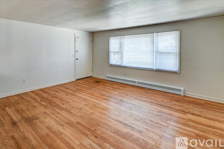 A room with wooden flooring and a window with blinds.