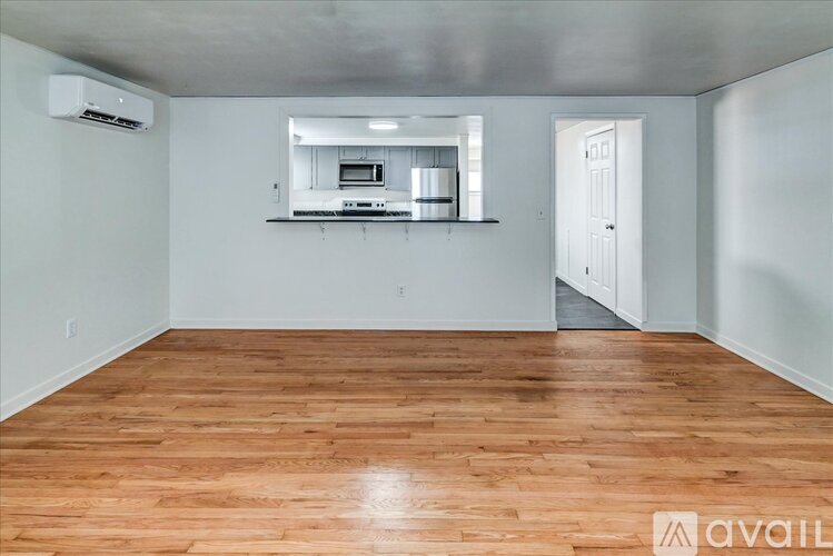 A room with wooden flooring and a window with blinds.