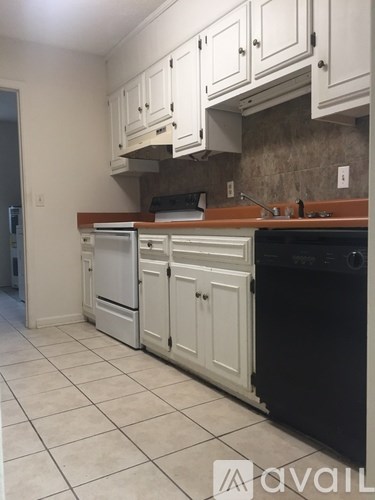 A kitchen with white cabinets and a black dishwasher.