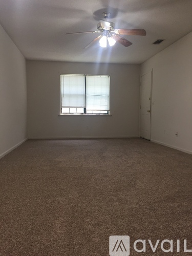 A room with a carpeted floor and a ceiling fan.