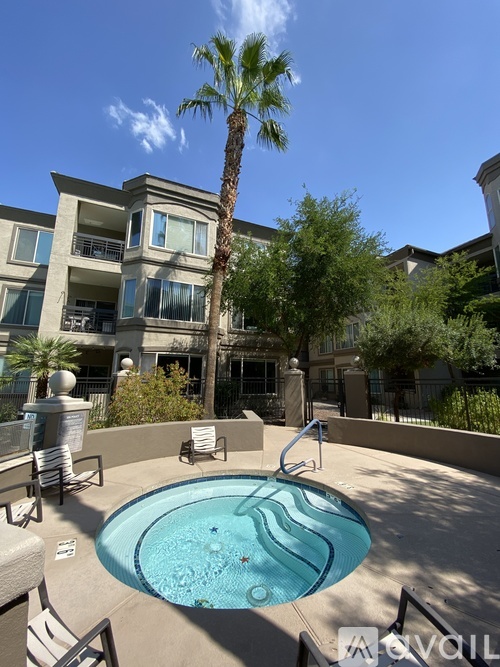 A pool surrounded by chairs and a palm tree in front of a building.