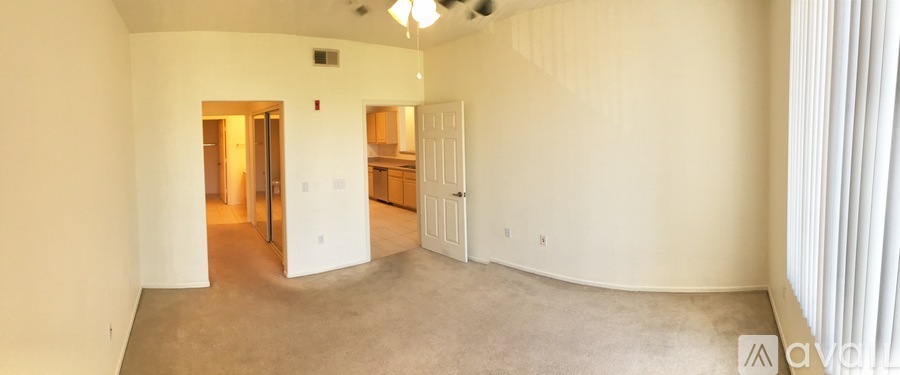 A spacious room with a kitchen area in the background.