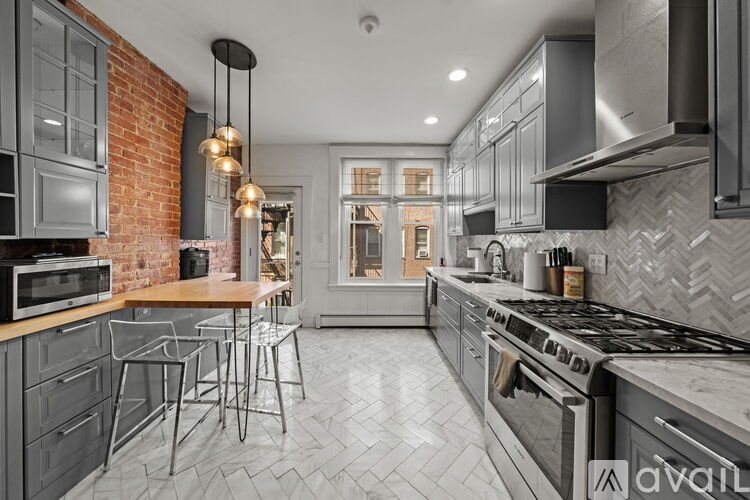 A modern kitchen with a brick wall and a marble countertop.