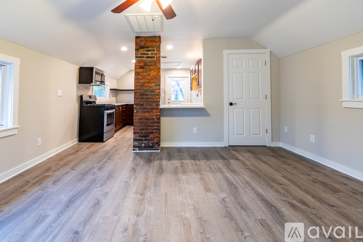 A living room with a brick fireplace and wood flooring.
