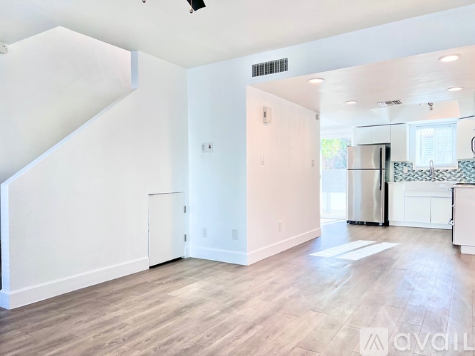 A spacious, empty room with wood flooring and a staircase to the left.