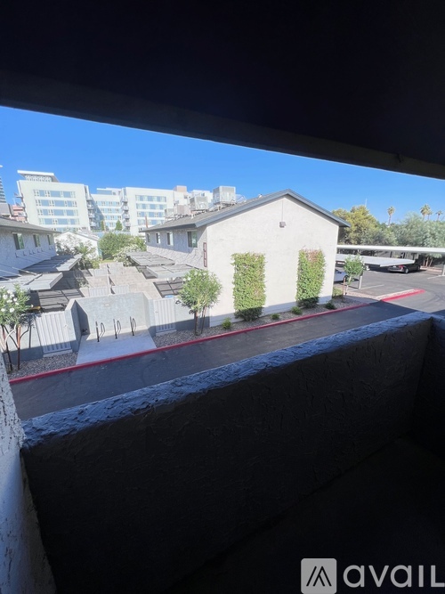 A balcony with a view of a parking lot and buildings.