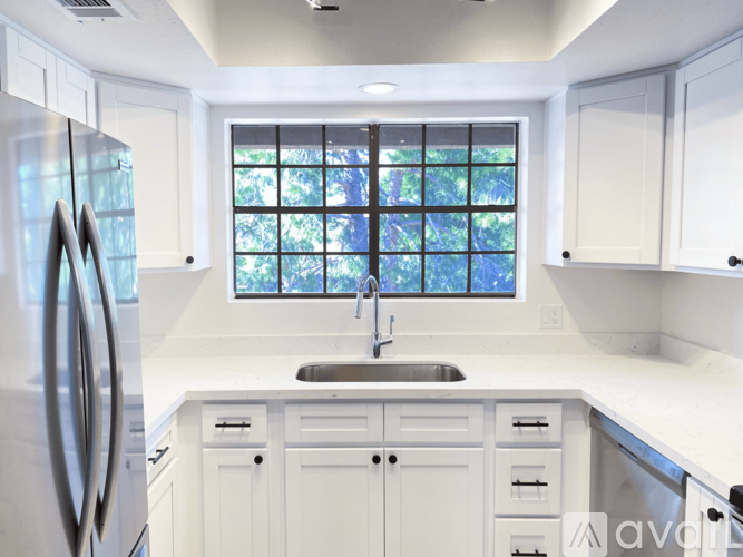 A modern kitchen with white cabinets and a stainless steel refrigerator.