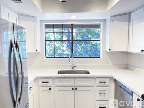 A modern kitchen with white cabinets and a stainless steel refrigerator.