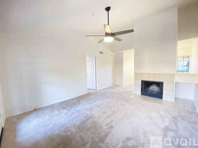 A spacious living room with a fireplace and a ceiling fan.