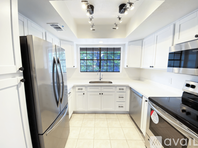 A kitchen with white cabinets and a black refrigerator.