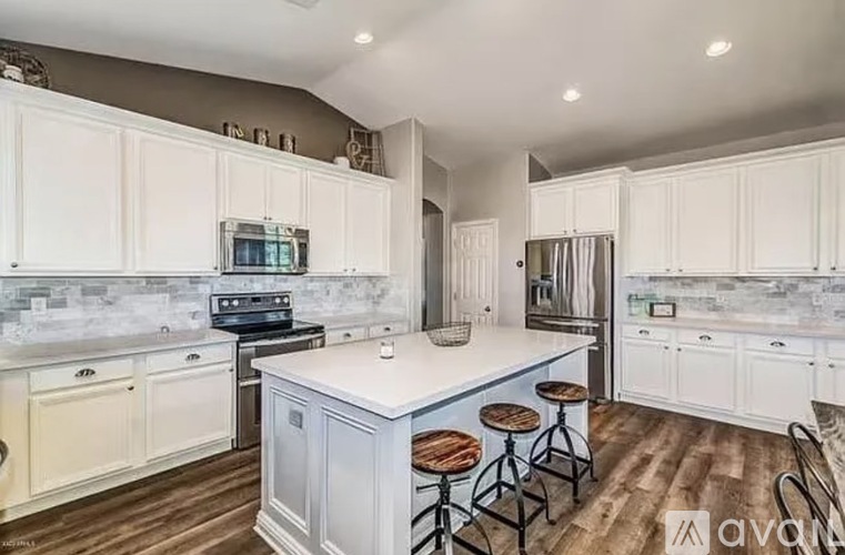 A kitchen with white cabinets and a blue island.