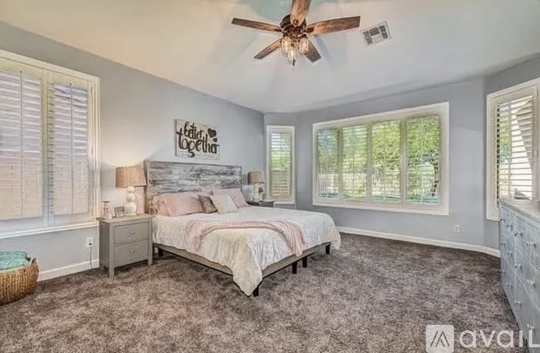 A bedroom with a bed, dresser, and window with blinds.