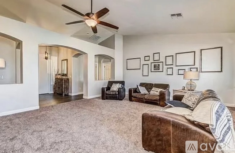 A living room with a brown couch and a ceiling fan.