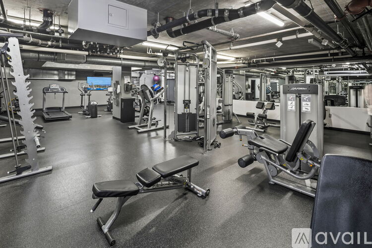A gym with a variety of equipment including a leg press machine, a squat rack, and a bench.