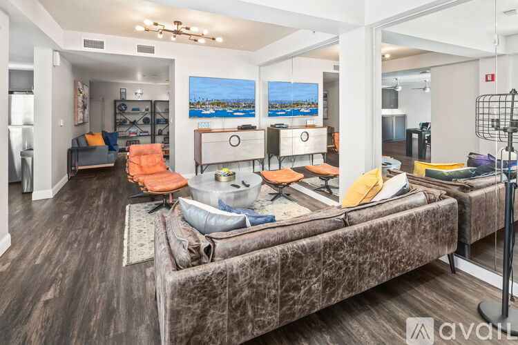 A living room with a large couch and a painting of a beach scene on the wall.