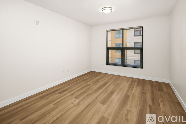 A room with wooden flooring and a window showing a building outside.