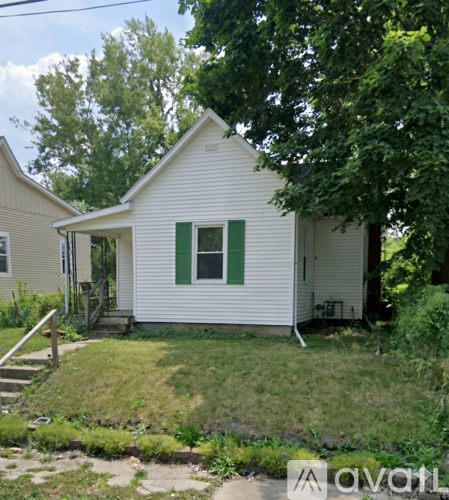 A white house with green shutters and a small porch.