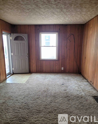 A room with a carpeted floor, a door, and a window.