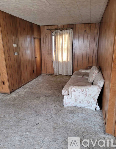 A room with wooden walls and a window with curtains.