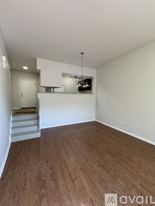 A room with wooden flooring and a staircase leading to another room.