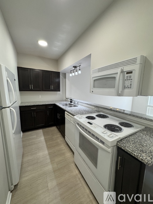 A kitchen with white appliances and black cabinets.