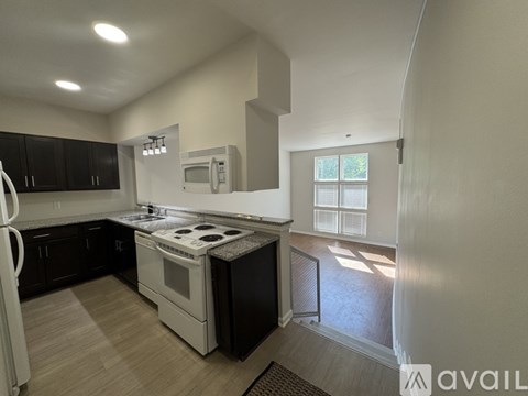 A kitchen with a white fridge, black cabinets, and a white stove top oven.