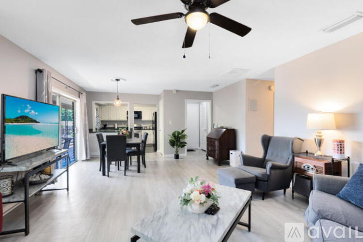 A living room with a flat screen TV and a ceiling fan.