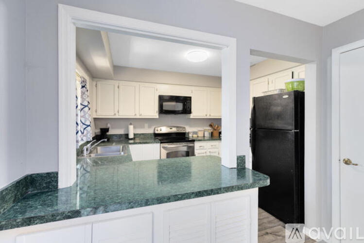 A kitchen with a black refrigerator and white cabinets.