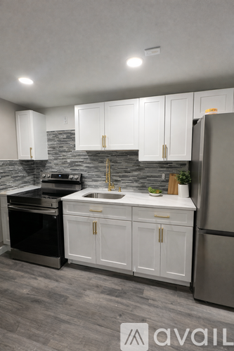 A kitchen with white cabinets and a grey backsplash.