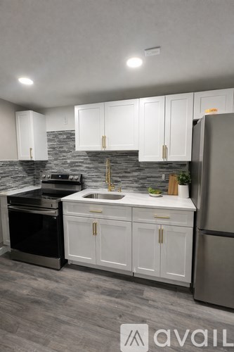 A kitchen with white cabinets and a grey backsplash.