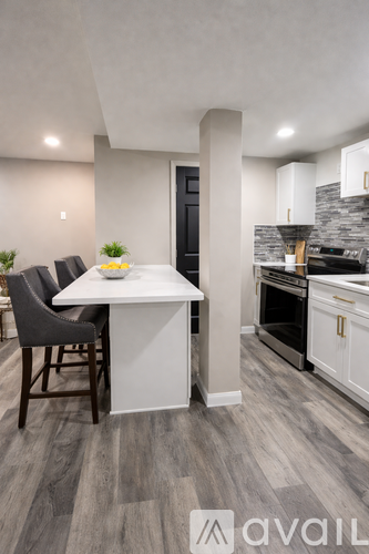 A modern kitchen with a white island and grey chairs.