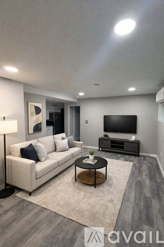 A modern living room with a white sofa, a black coffee table, and a flat-screen TV.