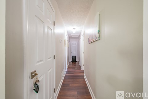 A long hallway with a door on the left and a picture on the wall on the right.