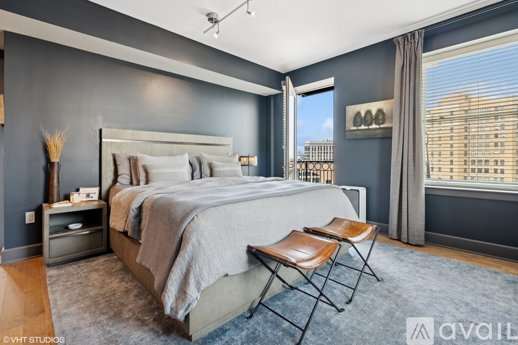 A bedroom with a large bed and a window overlooking a cityscape.