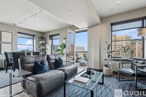 A modern living room with a large grey sofa and a glass coffee table.
