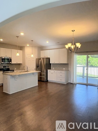 A modern kitchen with white cabinets and a wooden floor.
