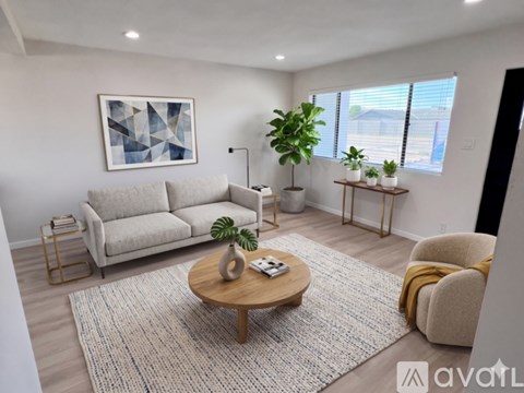 A living room with a grey couch, a wooden coffee table, a plant, and a painting on the wall.
