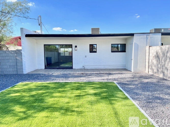 A modern house with a white exterior and a gravel yard.