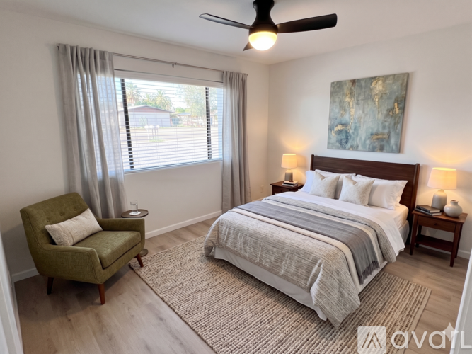 A bedroom with a bed, chair, and painting on the wall.