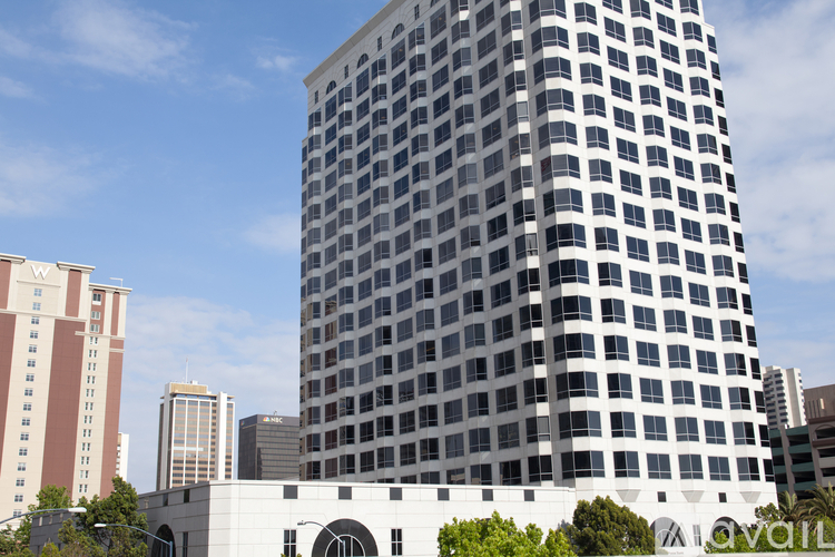 A tall building with a grid of windows stands in front of other buildings.